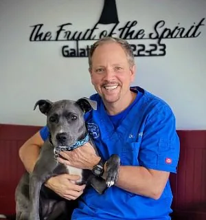 male doctor posing with dog on a bench
