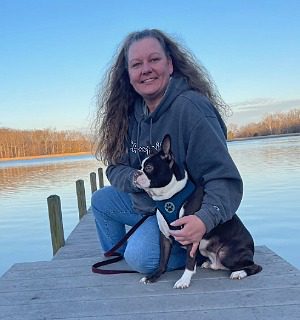 Female sitting on a pier with a French Bulldog